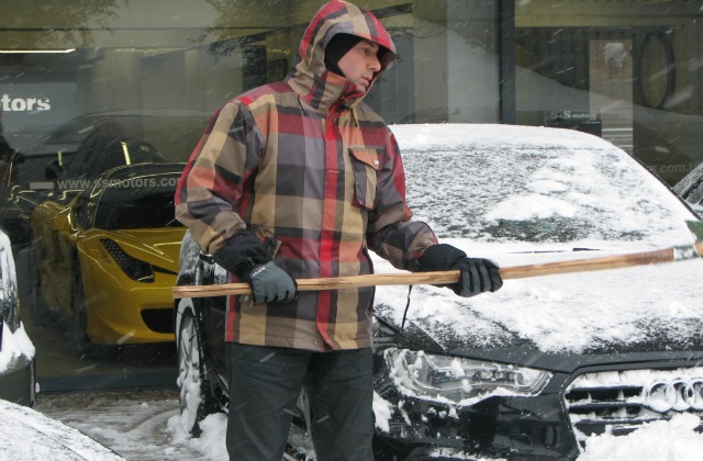 A man cleaning a car from snow.